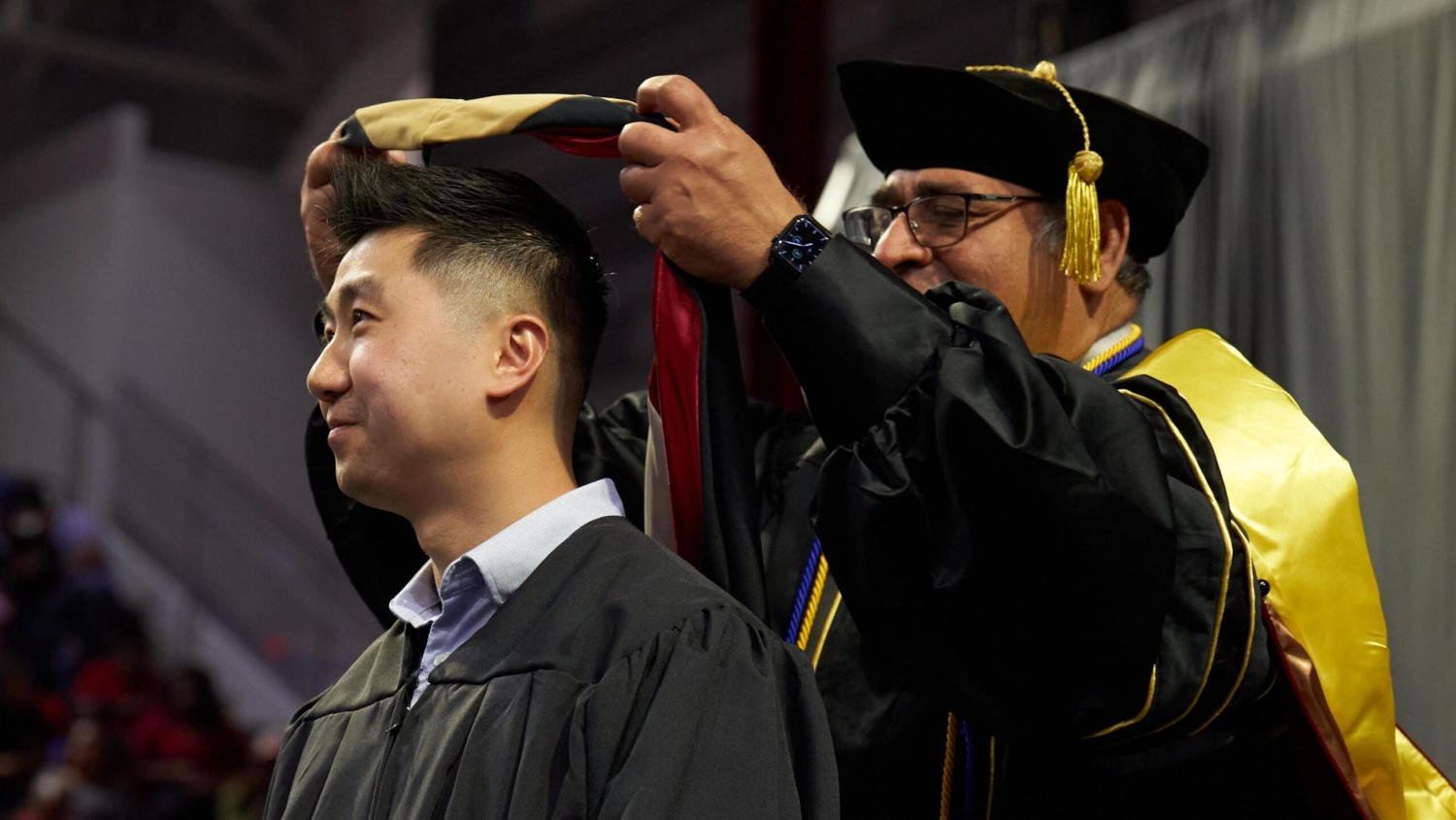 A student getting hooded at graduation.